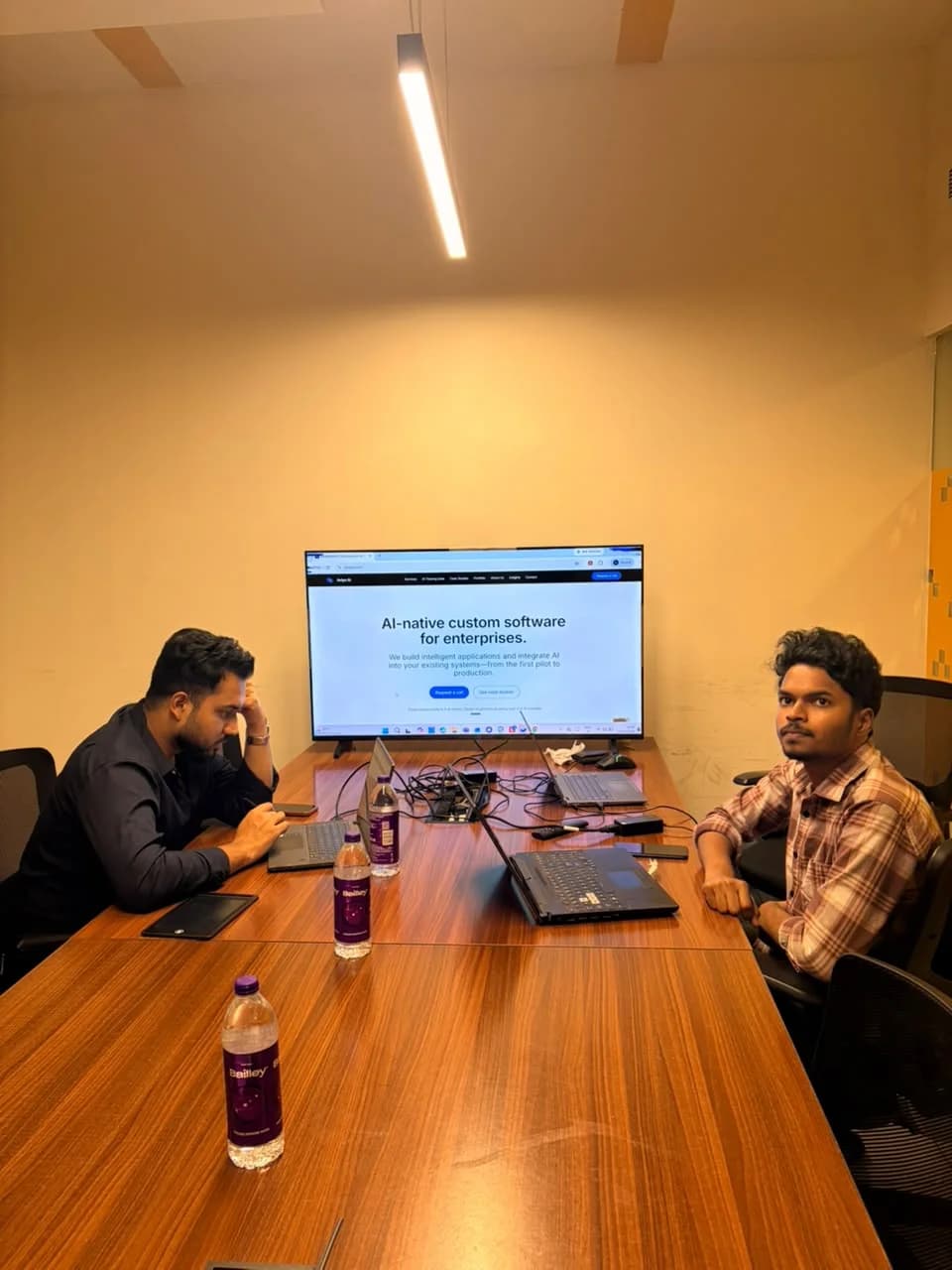 Avlys team members at the office conference table with their website displayed behind them.